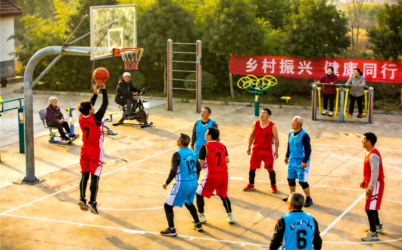 乡村文化广场上村民进行篮球比赛和健身活动的热闹场面
