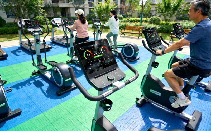 现代化社区智能健身器材区 - 居民使用带有电子屏幕的智能器械进行锻炼