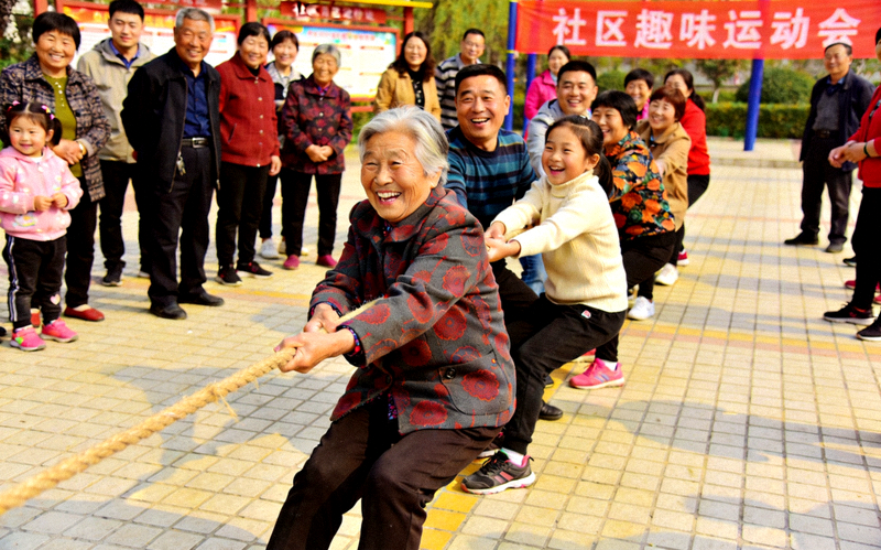 社区居民共同参加趣味运动会，不同代际的人们一起进行拔河比赛的欢乐场面