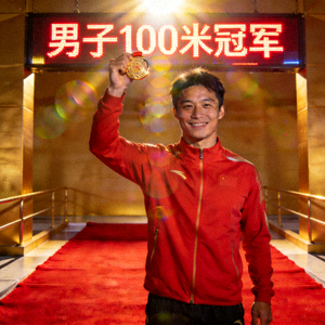 男子100米冠军陈浩在领奖台上手持金牌微笑